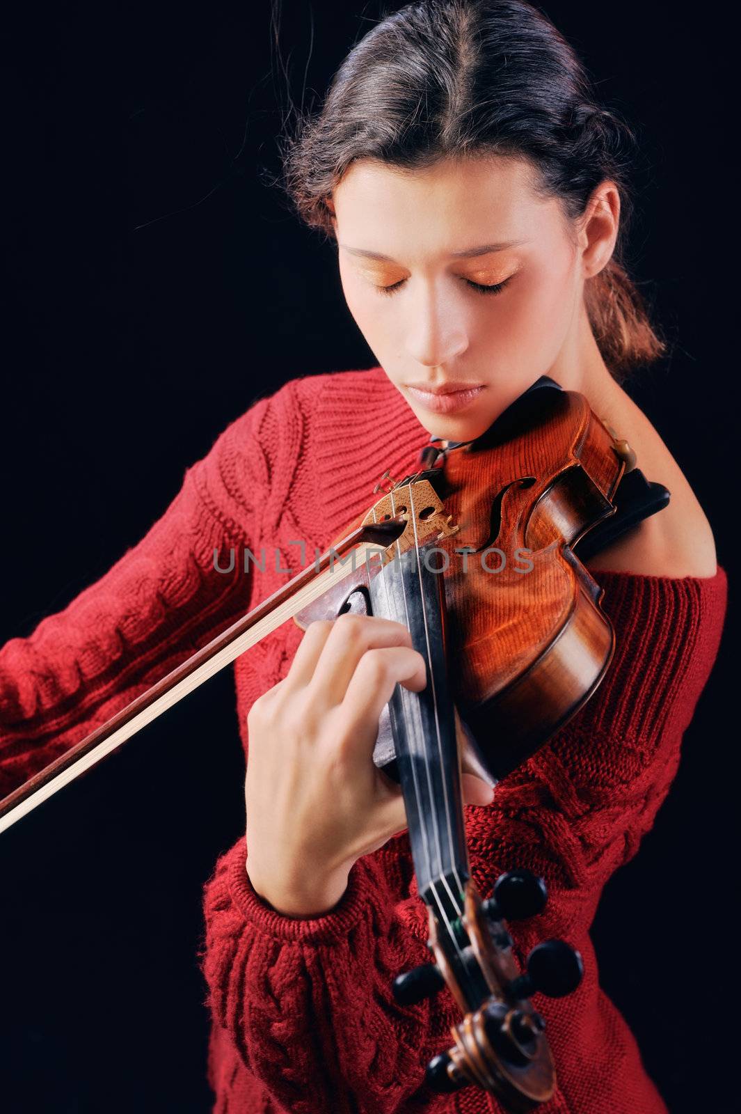 Young woman playing violin. Isolated on the black background