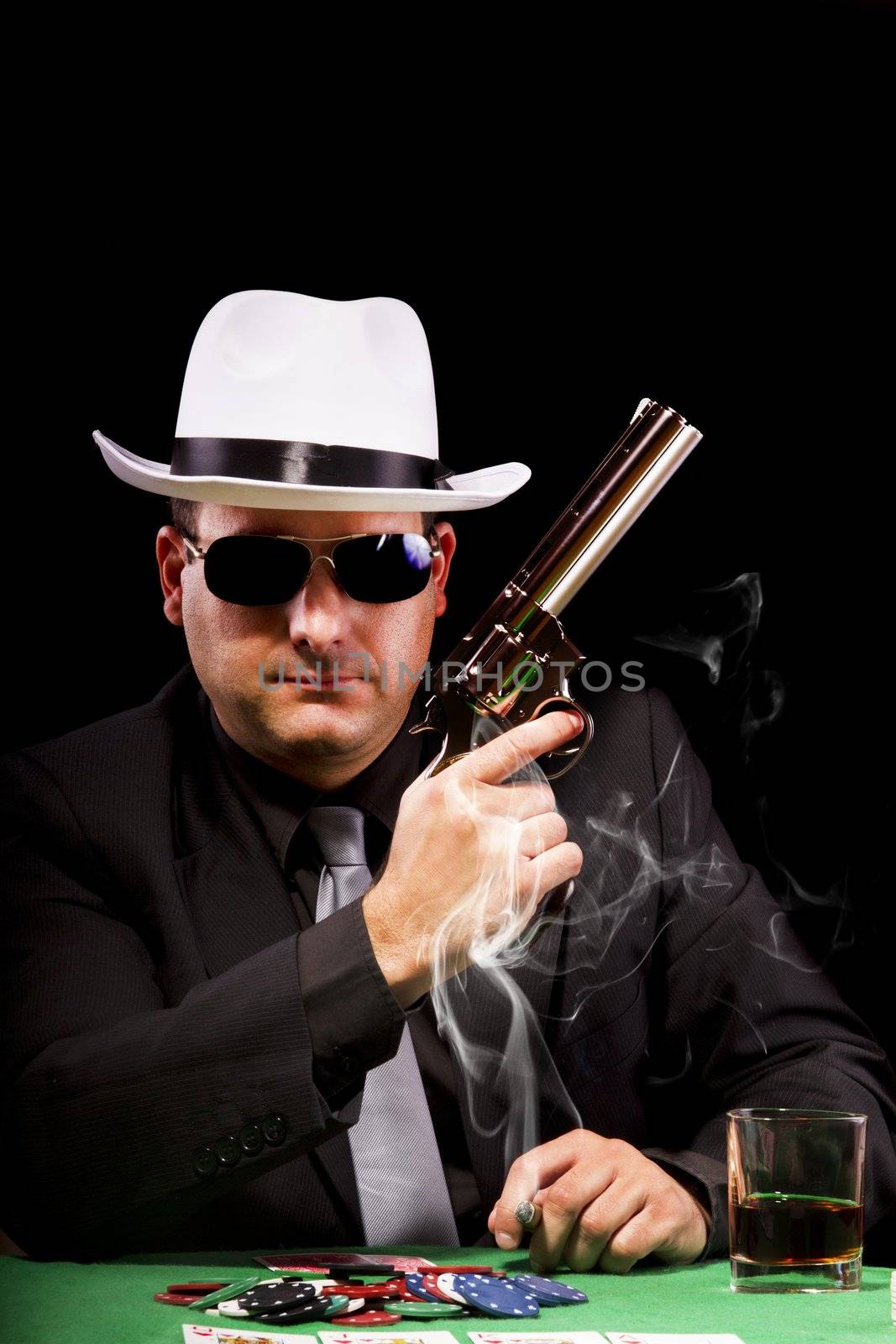View of a gangster man playing some cards and poker, smoking a Cuban cigar.