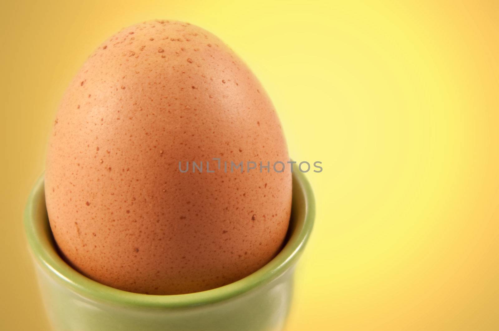 Close up boiled egg in ceramic cup with yellow background.