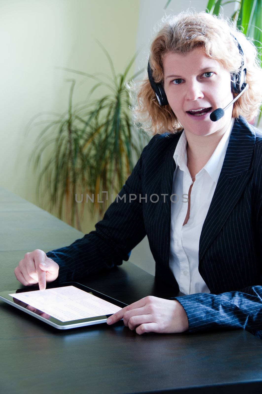 Closeup of a business woman using a tablet pc and talking into headset