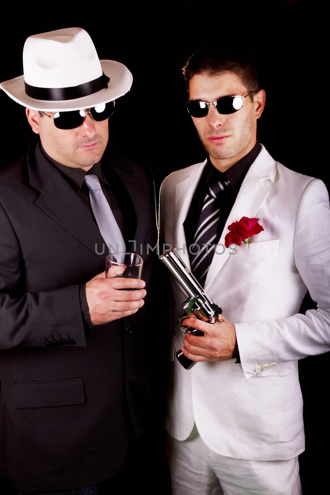 View of two gangster males holding a gun on a black background.