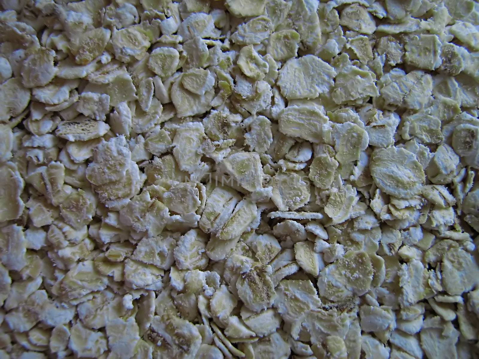 A photograph of uncooked oatmeal detailing its texture.
