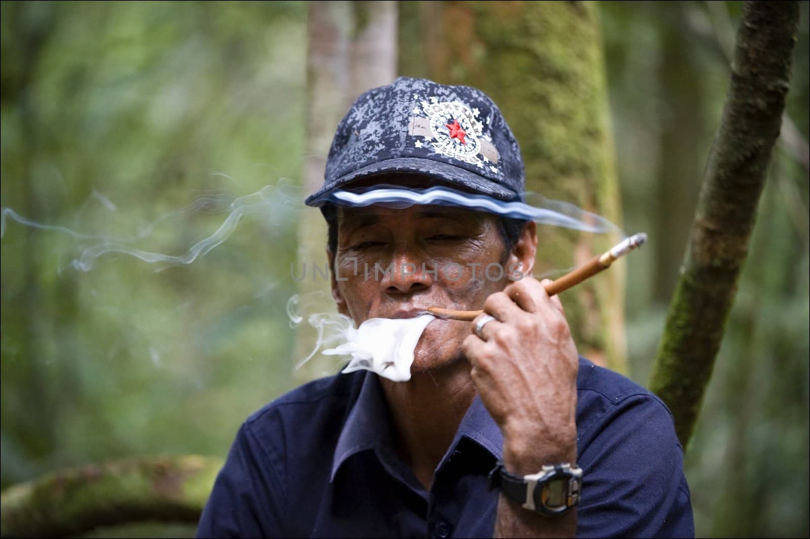 CAMP LEAKI. BORNEO ISLAND, INDONESIA. 2008 MAY  4: Umar - the Indonesian guide, smokes a cigaret. Wood of Borneo. Indonesia. On May, 4th, 2008. Indonesia. Borneo