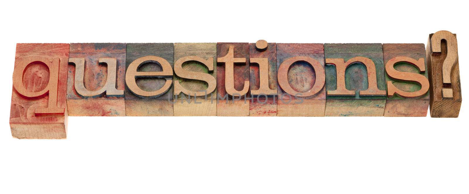 Questions? A word in vintage wooden letterpress printing blocks, stained by color inks, isolated on white