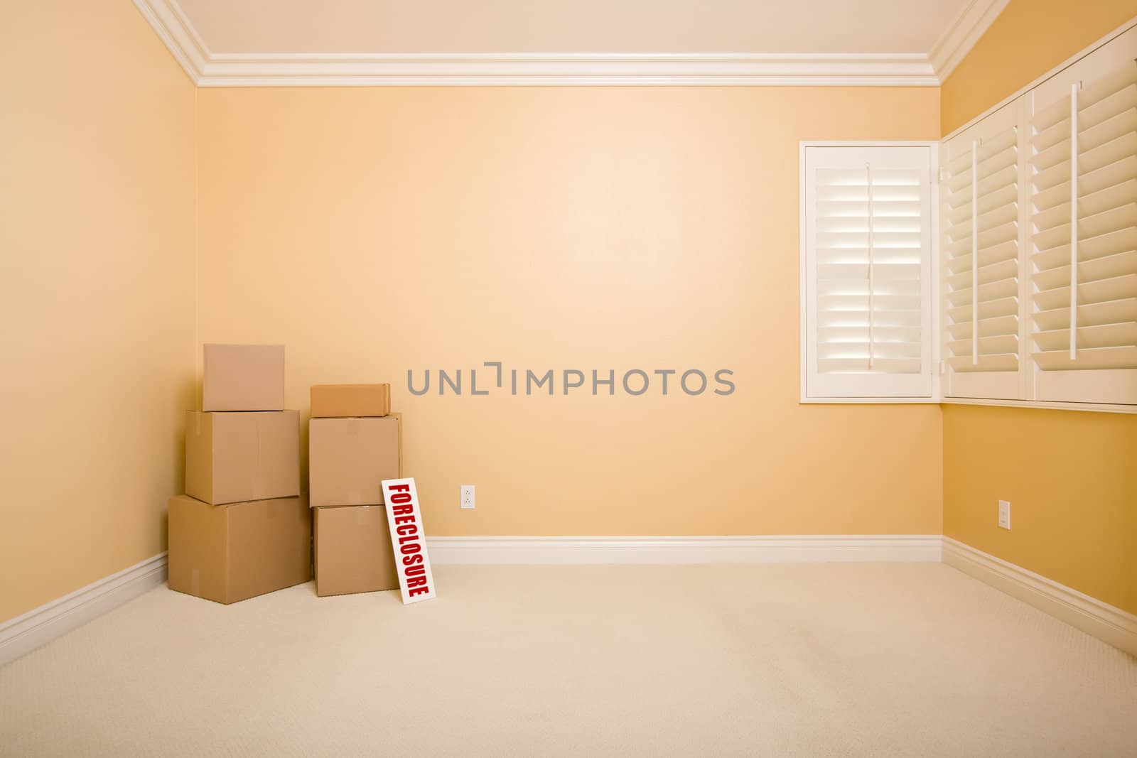 Moving Boxes and Foreclosure Real Estate Sign on Floor in Empty Room with Copy Space on Blank Wall.