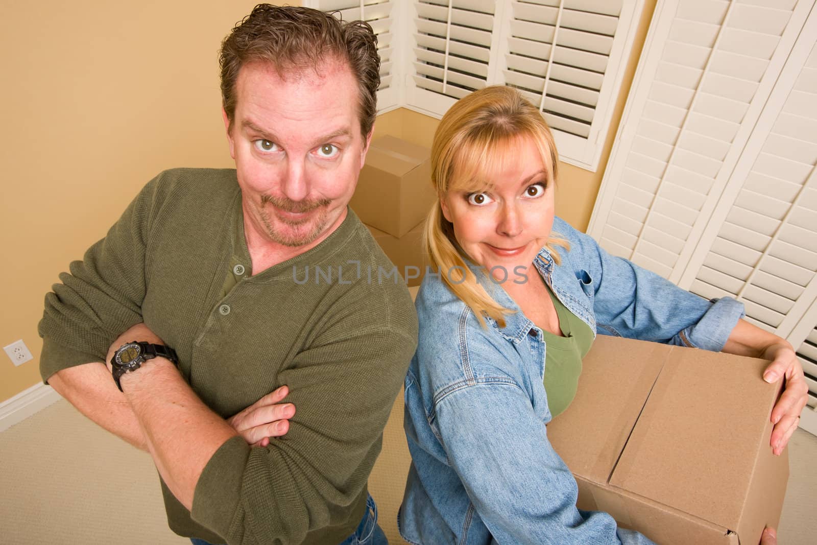 Smiling Goofy Couple and Moving Boxes in Empty Room.