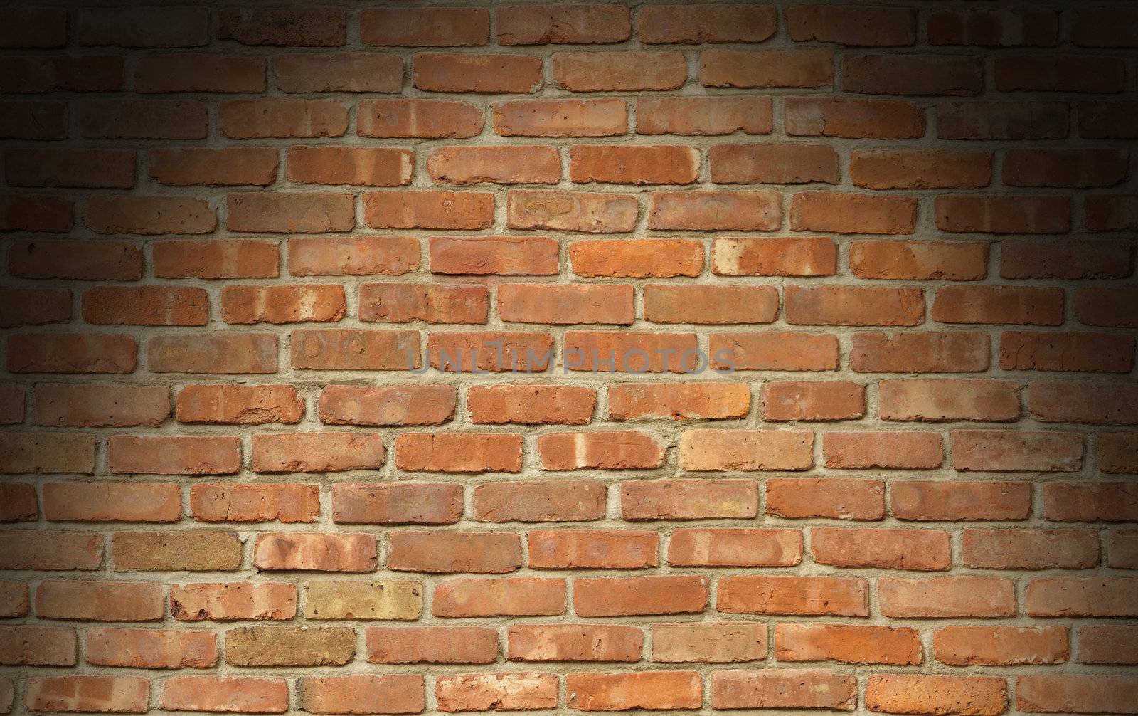 Weathered red brick wall texture lit dramatically from above