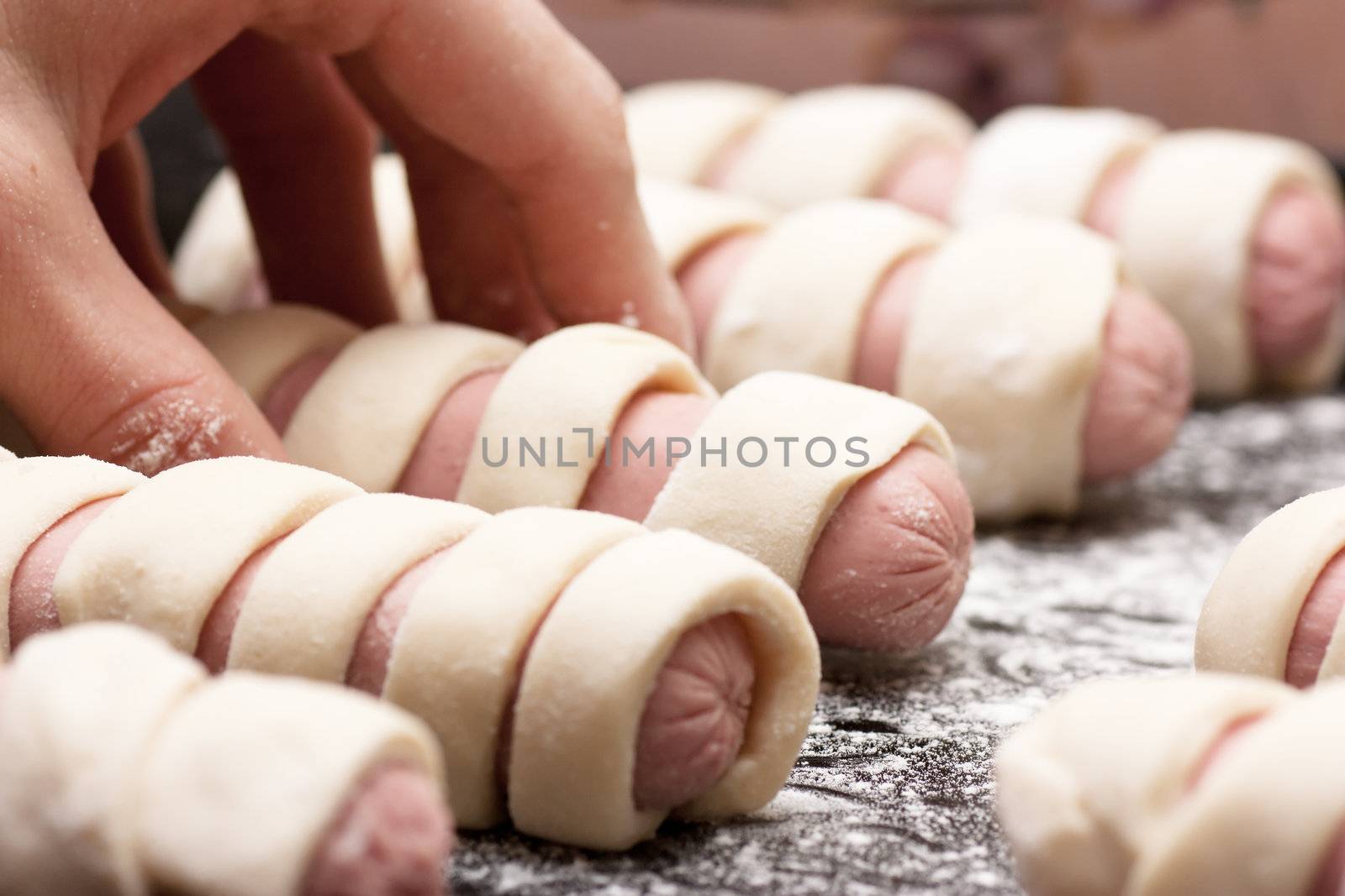 Raw sausage rolls in pastry on a baking tray