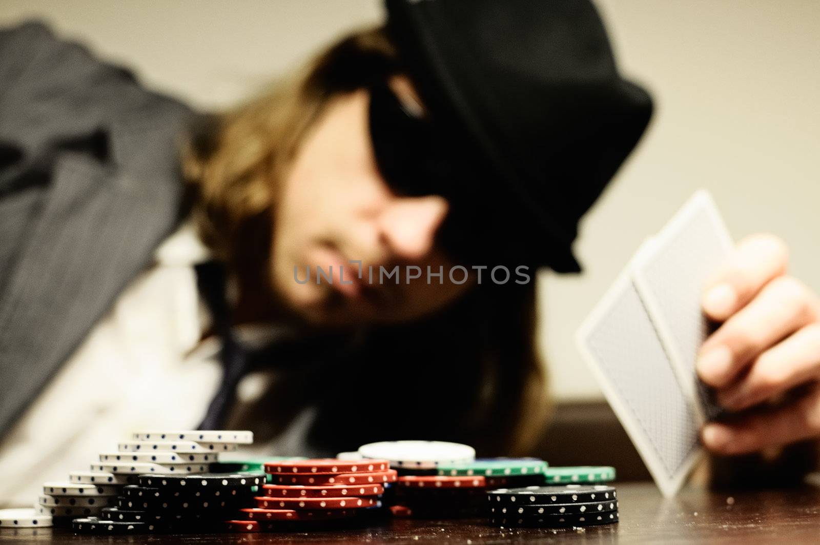 Man with hat and glasses playing underground poker.