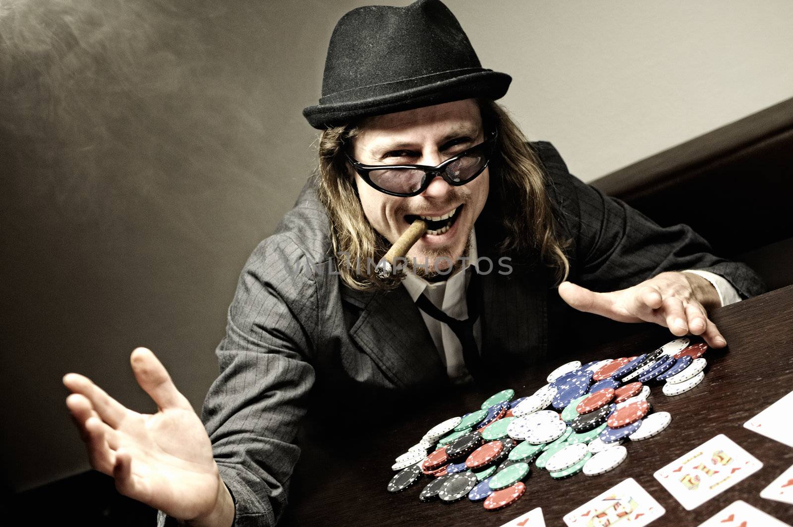 Man with hat and glasses playing underground poker.