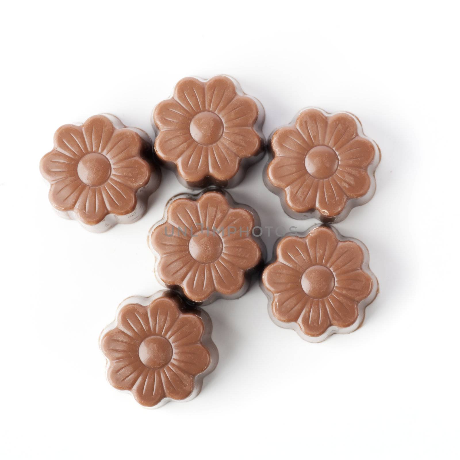 Five flower shaped milk chocolate candies on a white background.