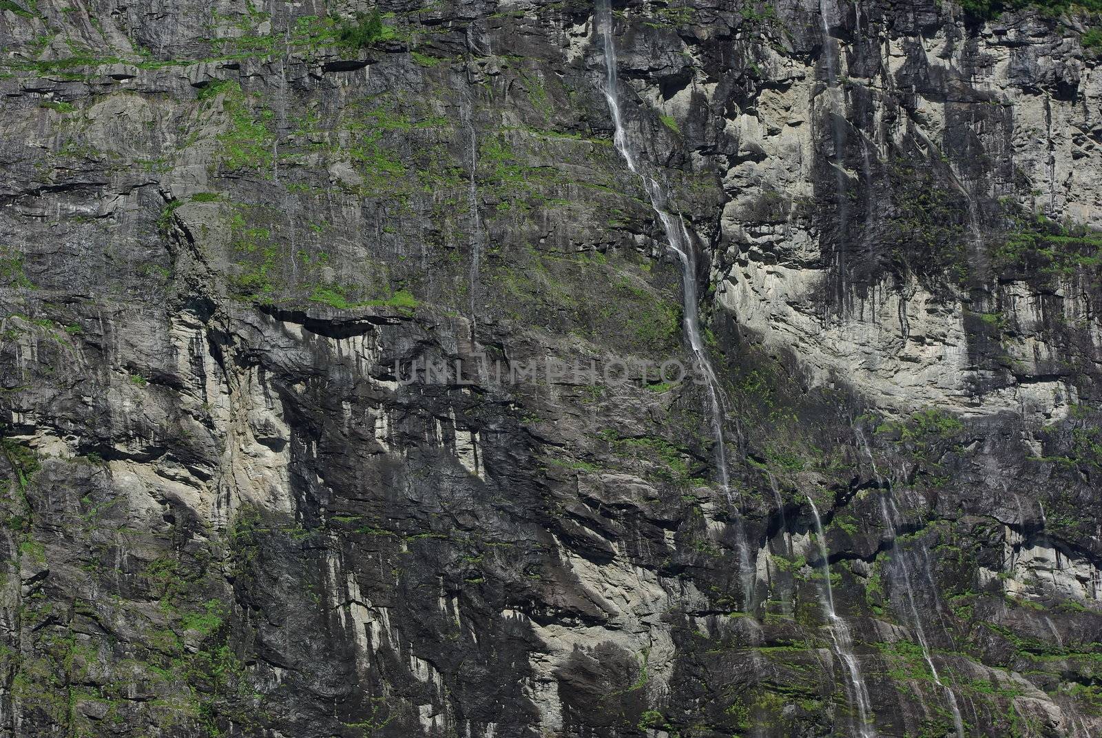 Rocky coastline of fjord with lot of springs and waterfalls in Geiranger, Norway