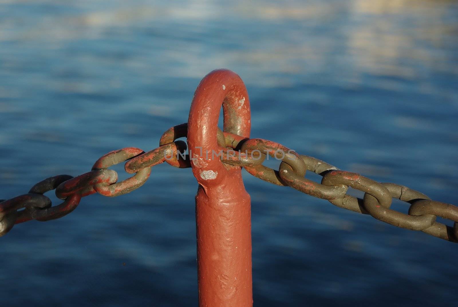 Old rusty fence made of chain on sea embankment