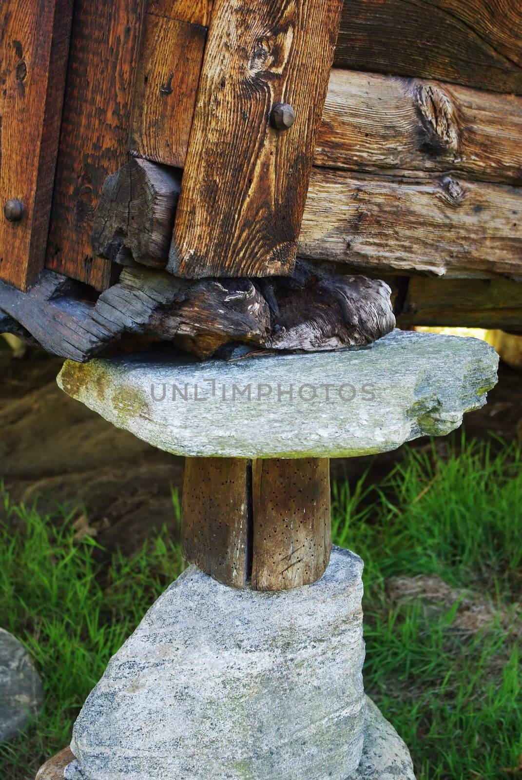 Corner of old wooden house, backed by stones and logs
