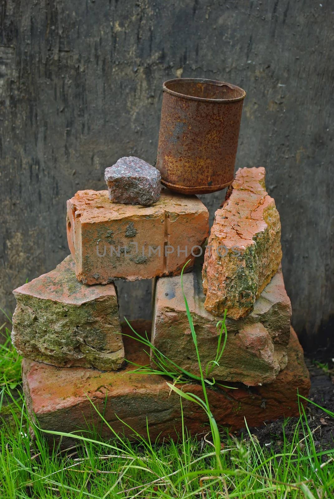 Humorous feng shui composition with brocken bricks and rusty can on dirty wood background