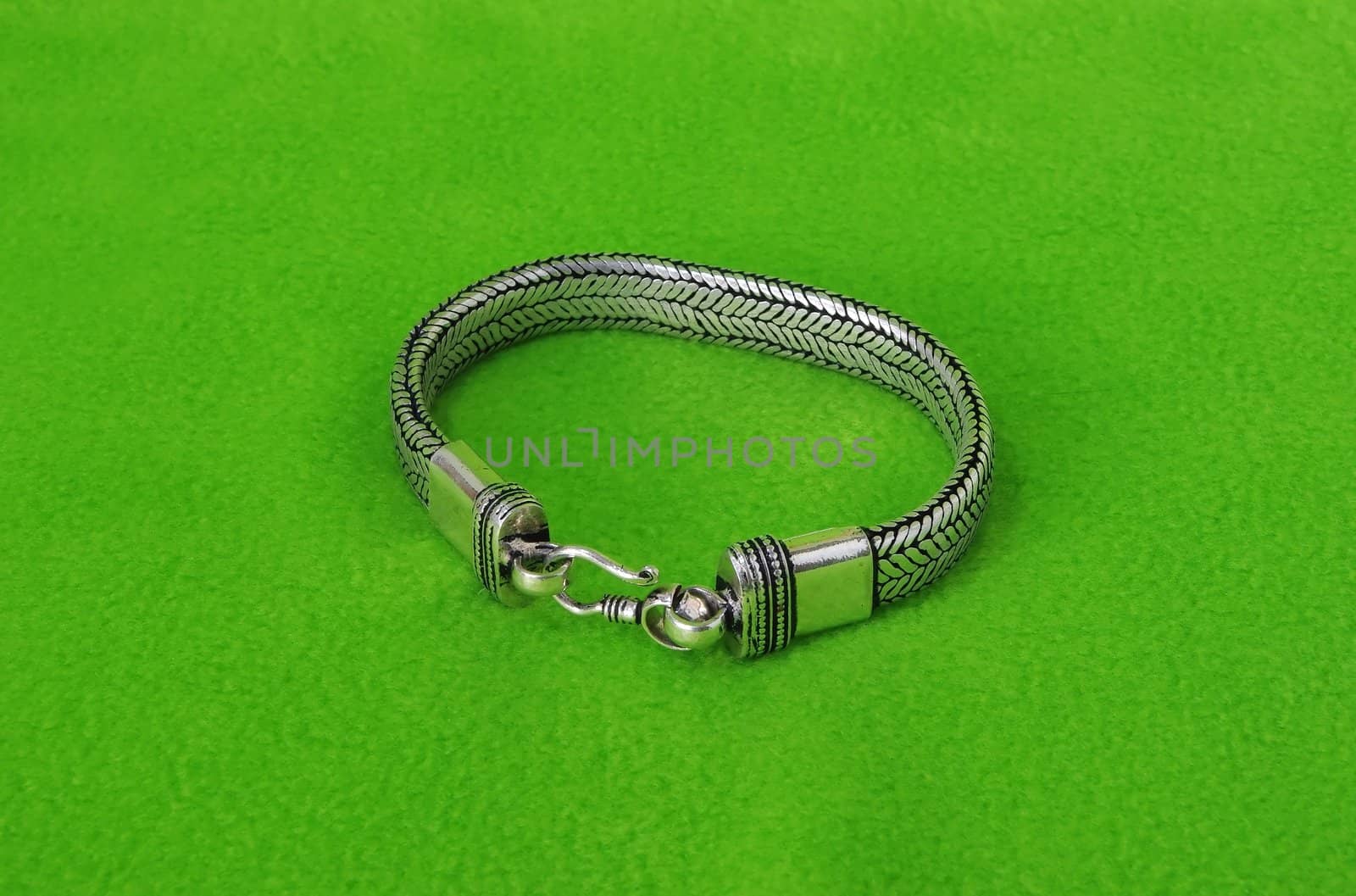 Style steel bracelet on green velvet background
