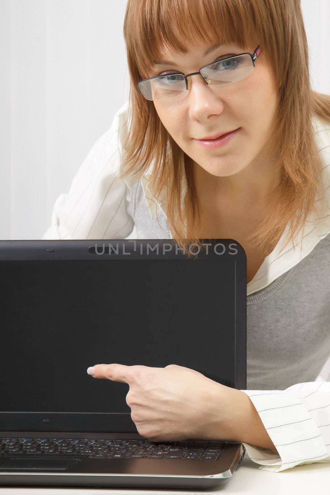 girl with glasses shows a finger on a laptop monitor. Close-up
