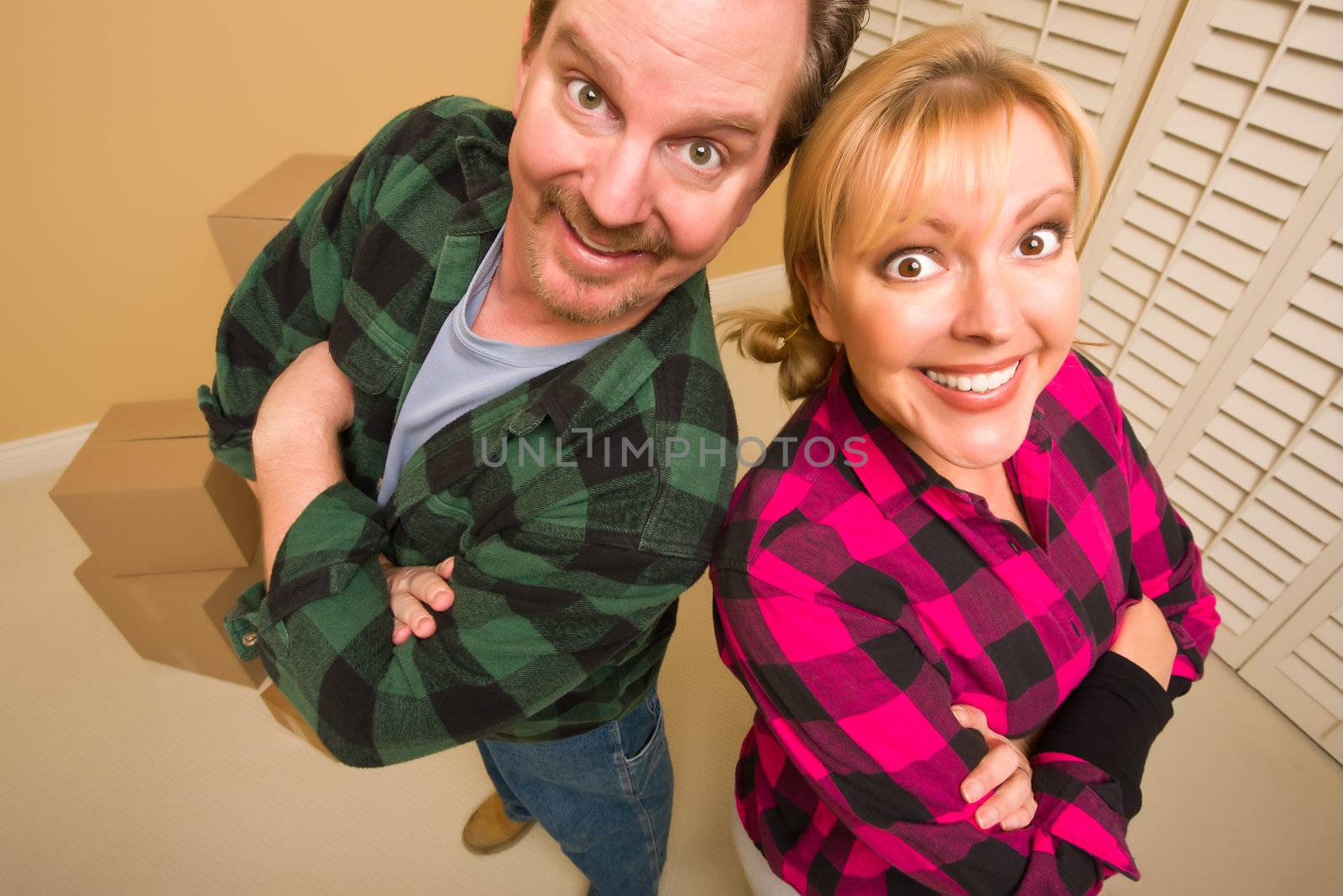 Proud Smiling Goofy Couple and Moving Boxes in Empty Room.