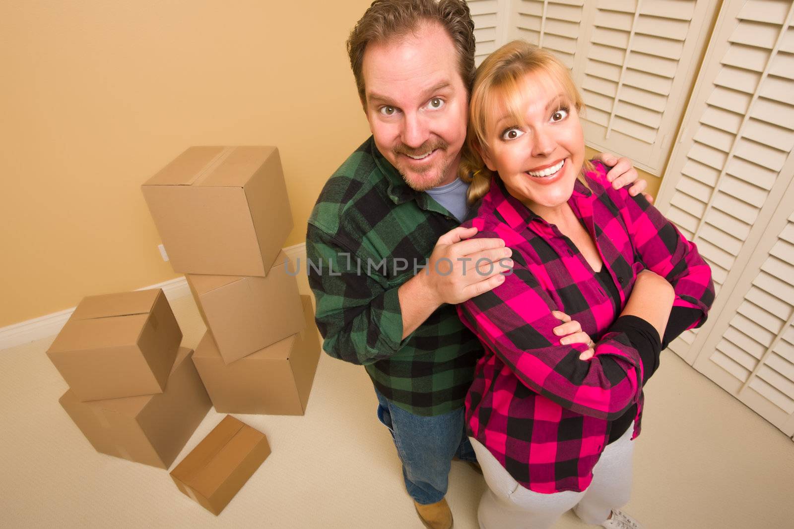 Proud Smiling Goofy Couple and Moving Boxes in Empty Room.