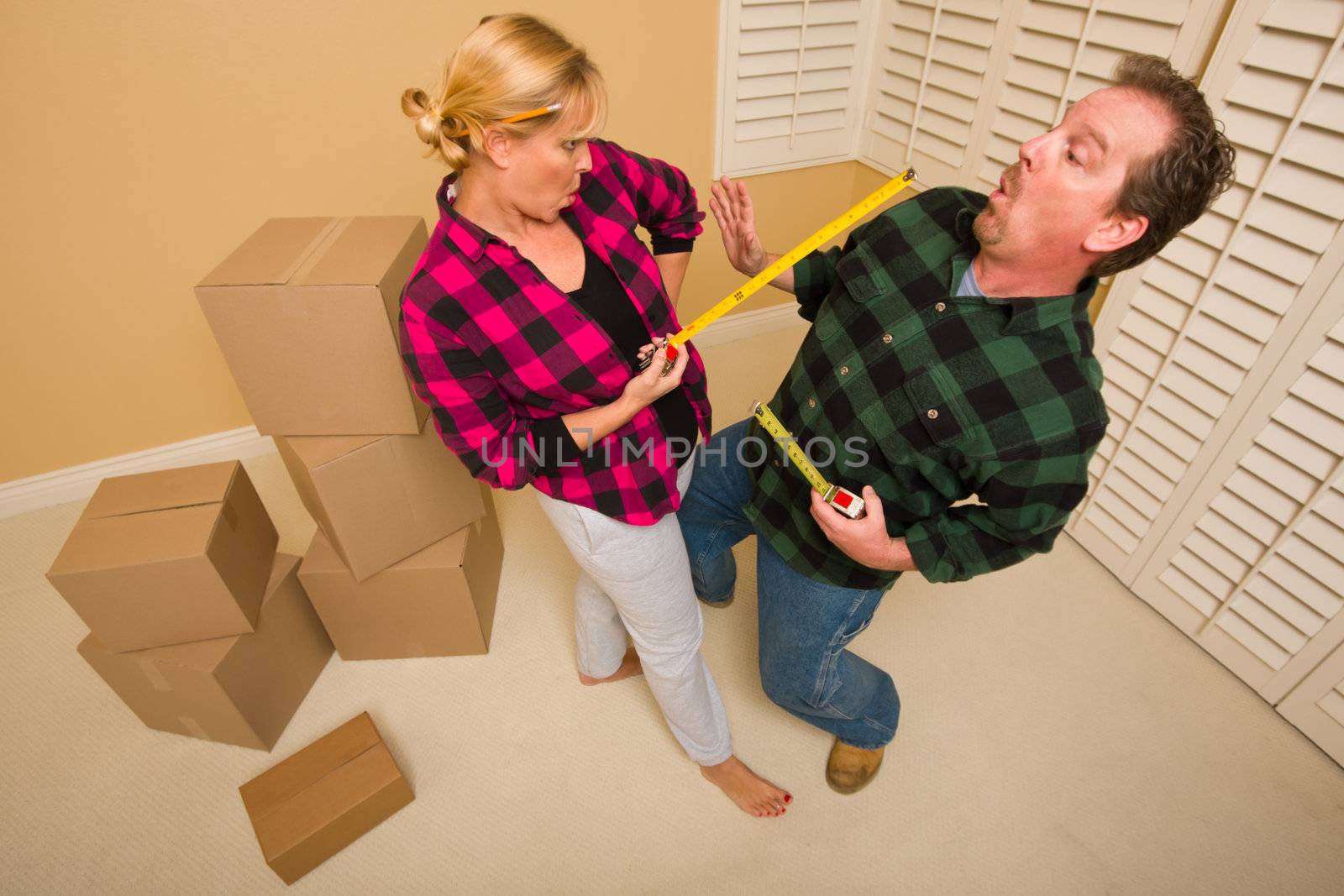 Couple Having a Fun Sword Fight with Their Tape Measures Surrounded by Packed Moving Boxes.