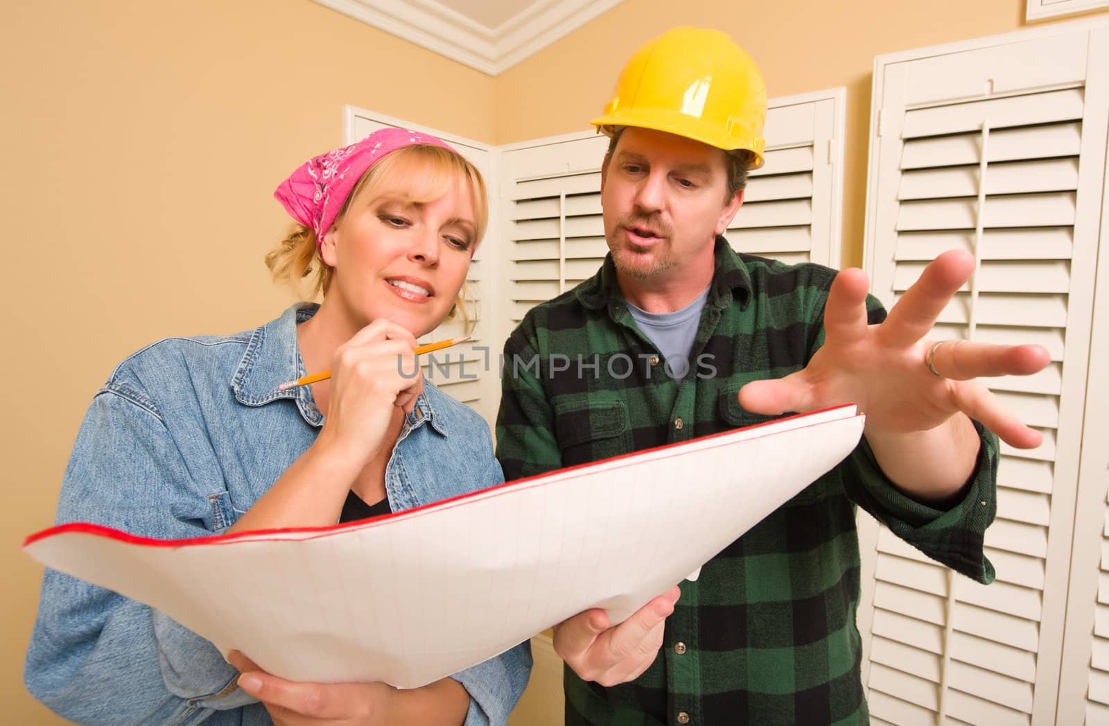 Male Contractor in Hard Hat Discussing Plans with Woman in Room.