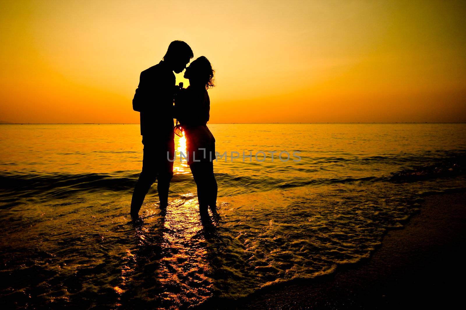 Silhouette of a young romantic couple  on sunset by phalakon