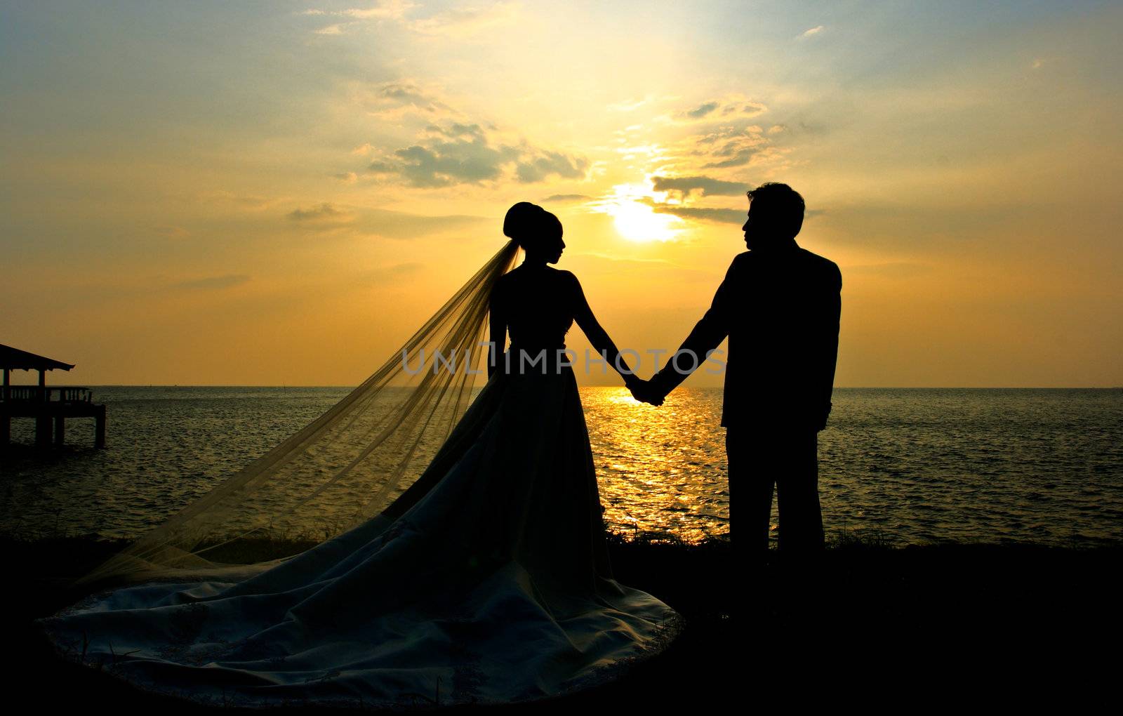 Wedding couple sillhouette at sunset by phalakon