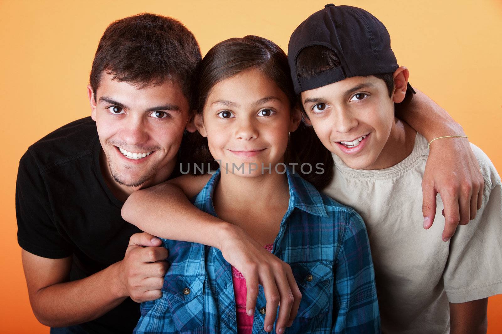Caring brothers with their sister smiling on orange background