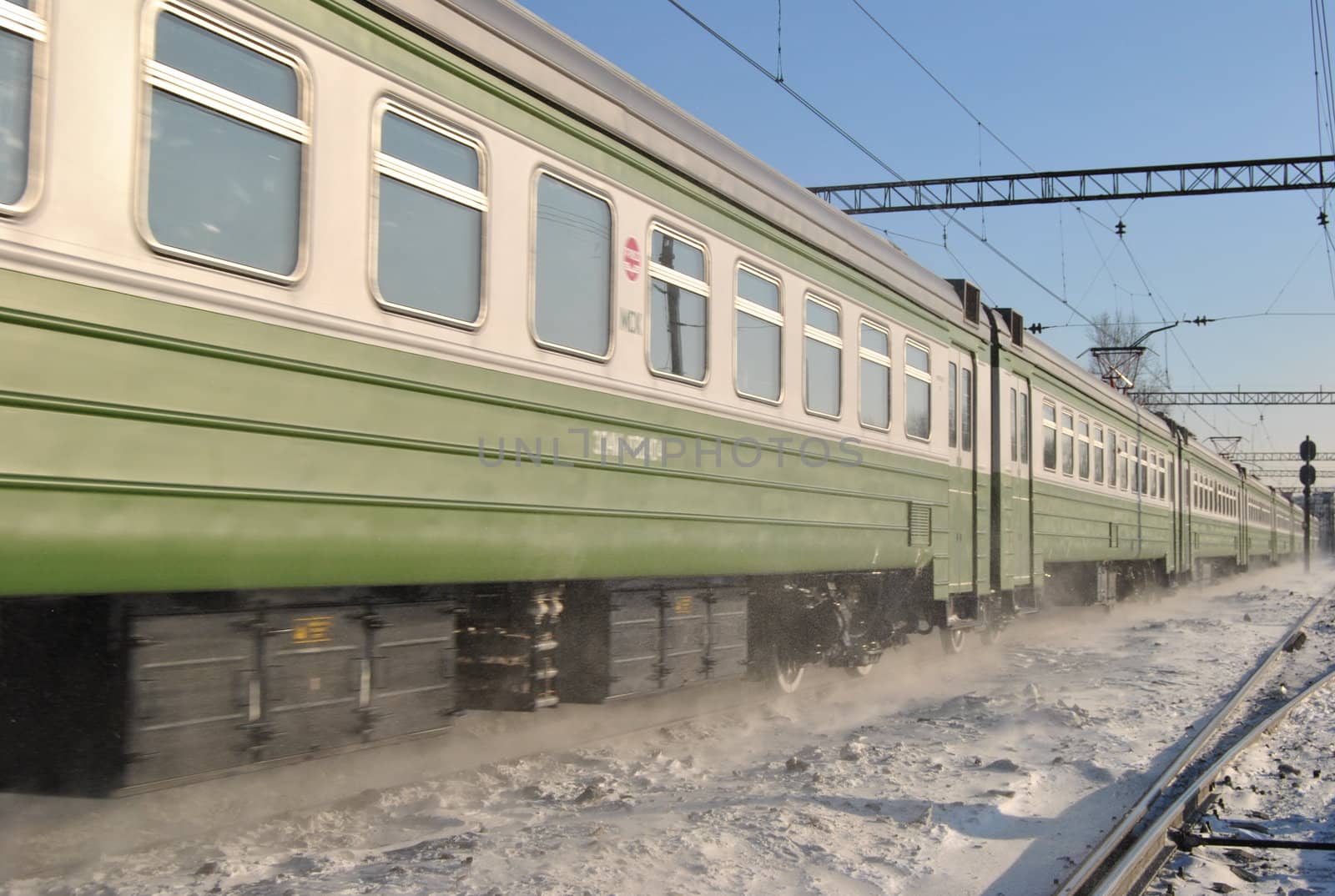 A passenger train travels on a snowy winter rail