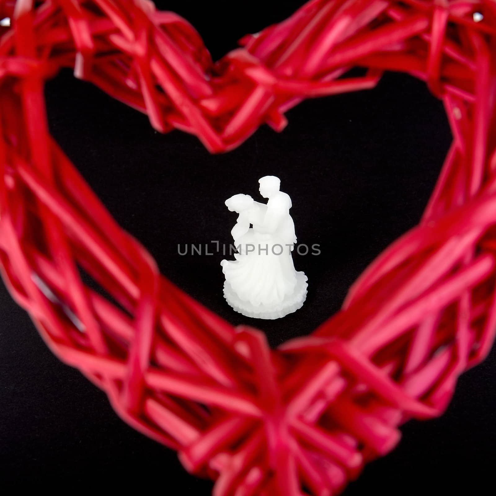 a bride an groom in white behind a red heart