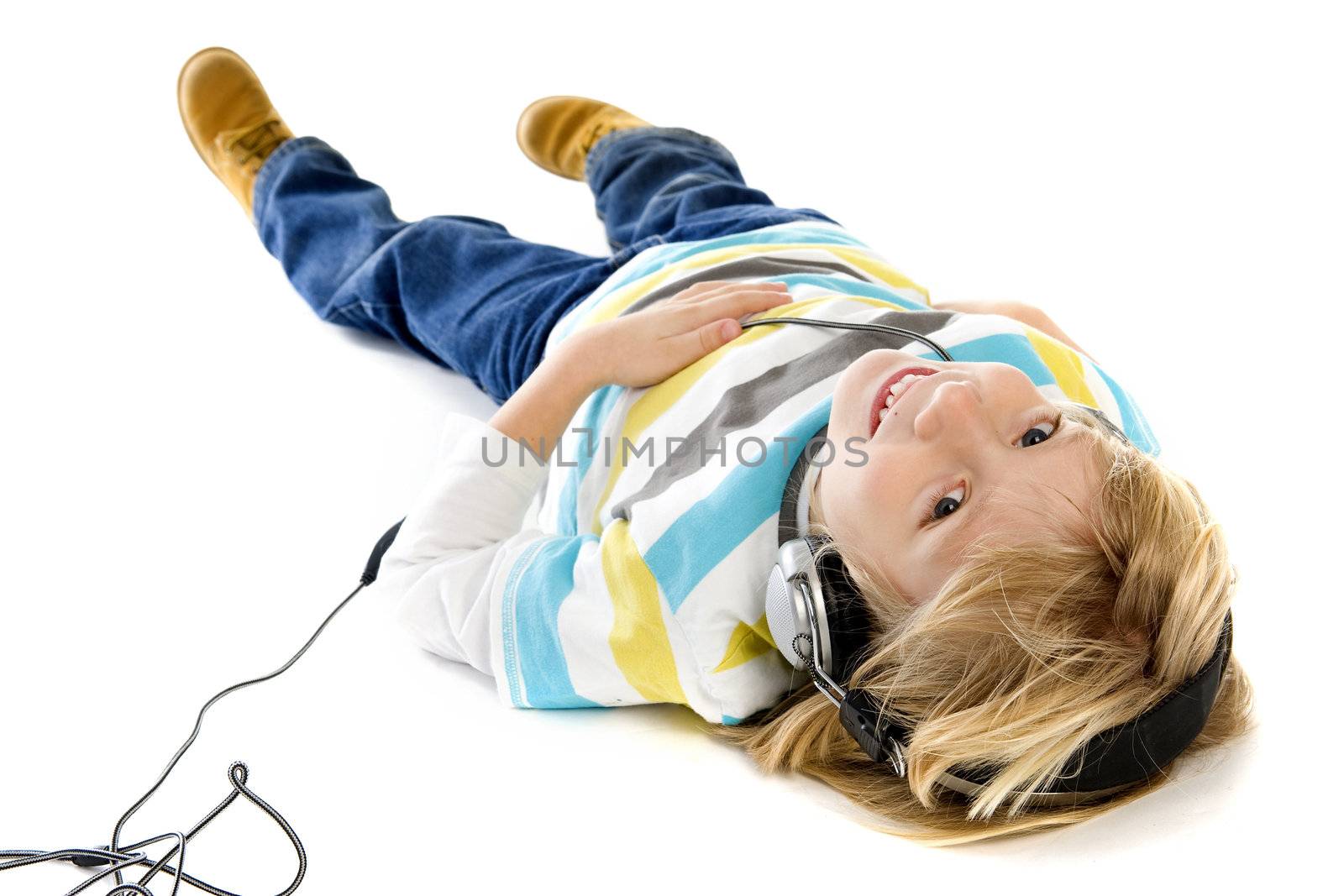 a little boy, laying on the ground, listening to music with a headphone