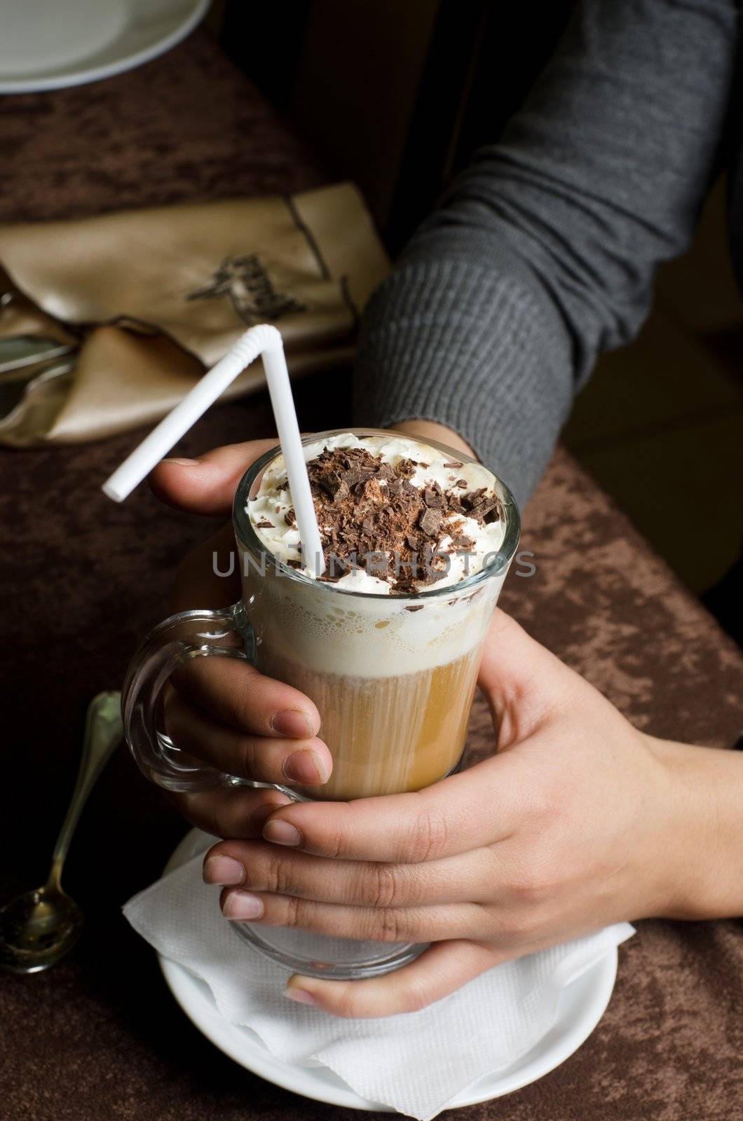 Closeup of female hands holding cup of latte