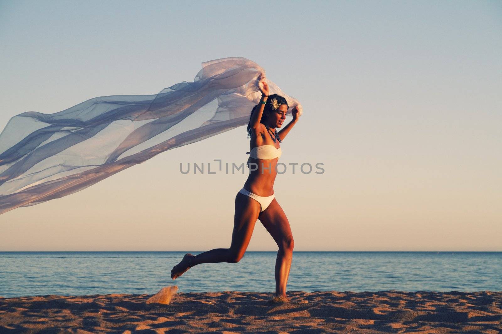 View of a beautiful young girl with a white bikini running on the beach.