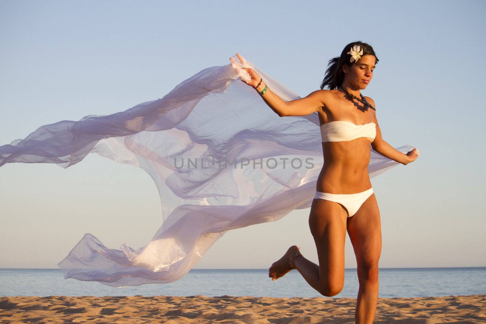 View of a beautiful young girl with a white bikini running on the beach.