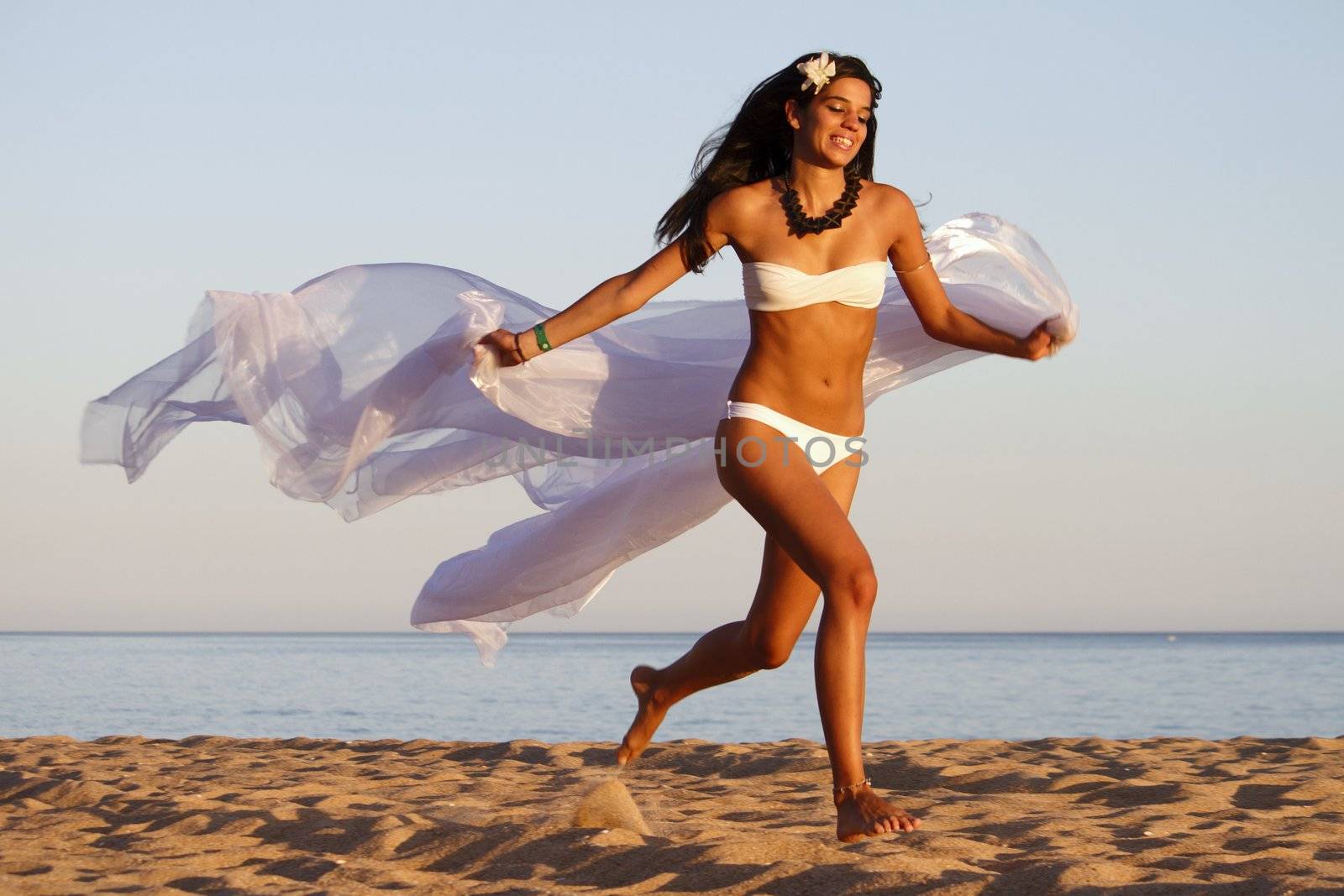 View of a beautiful young girl with a white bikini running on the beach.