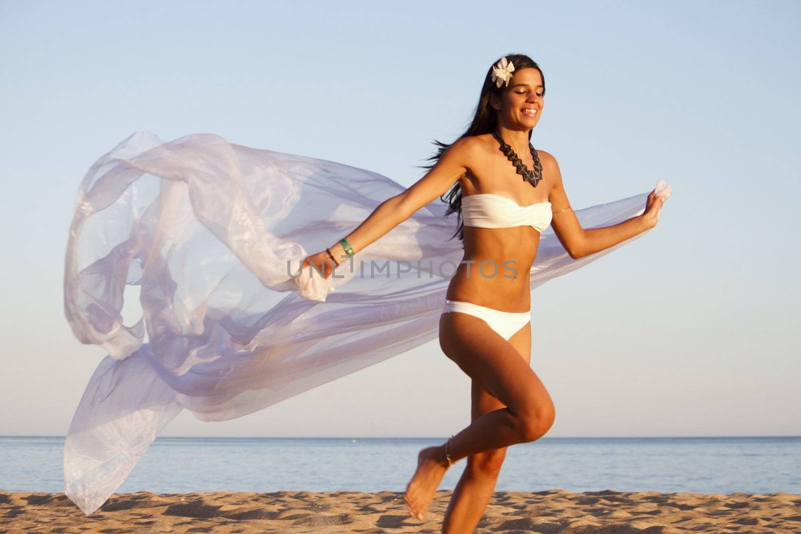 View of a beautiful young girl with a white bikini running on the beach.