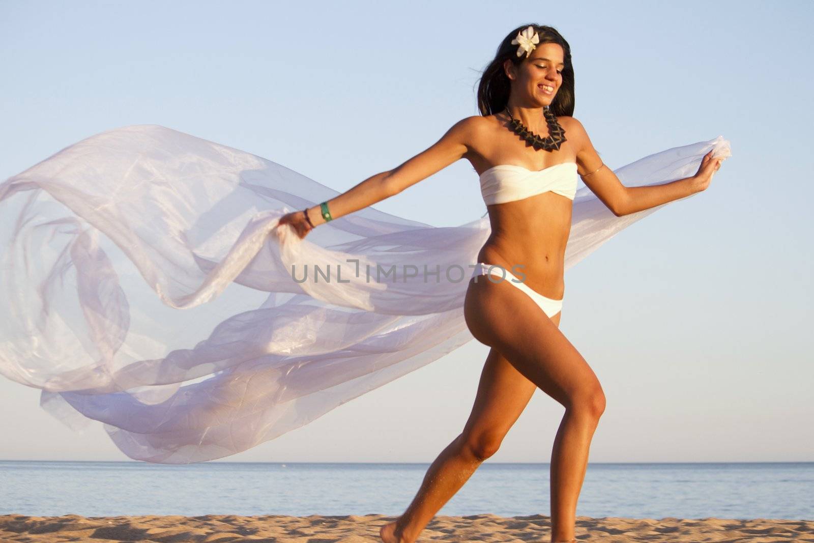 View of a beautiful young girl with a white bikini running on the beach.