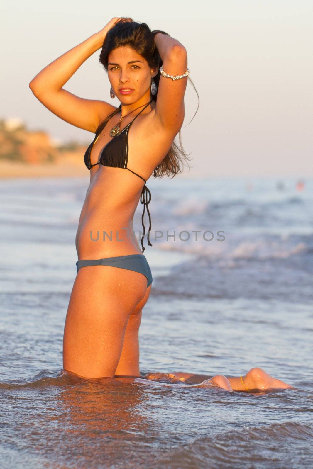 View of a beautiful young girl with a bikini standing on the shore.