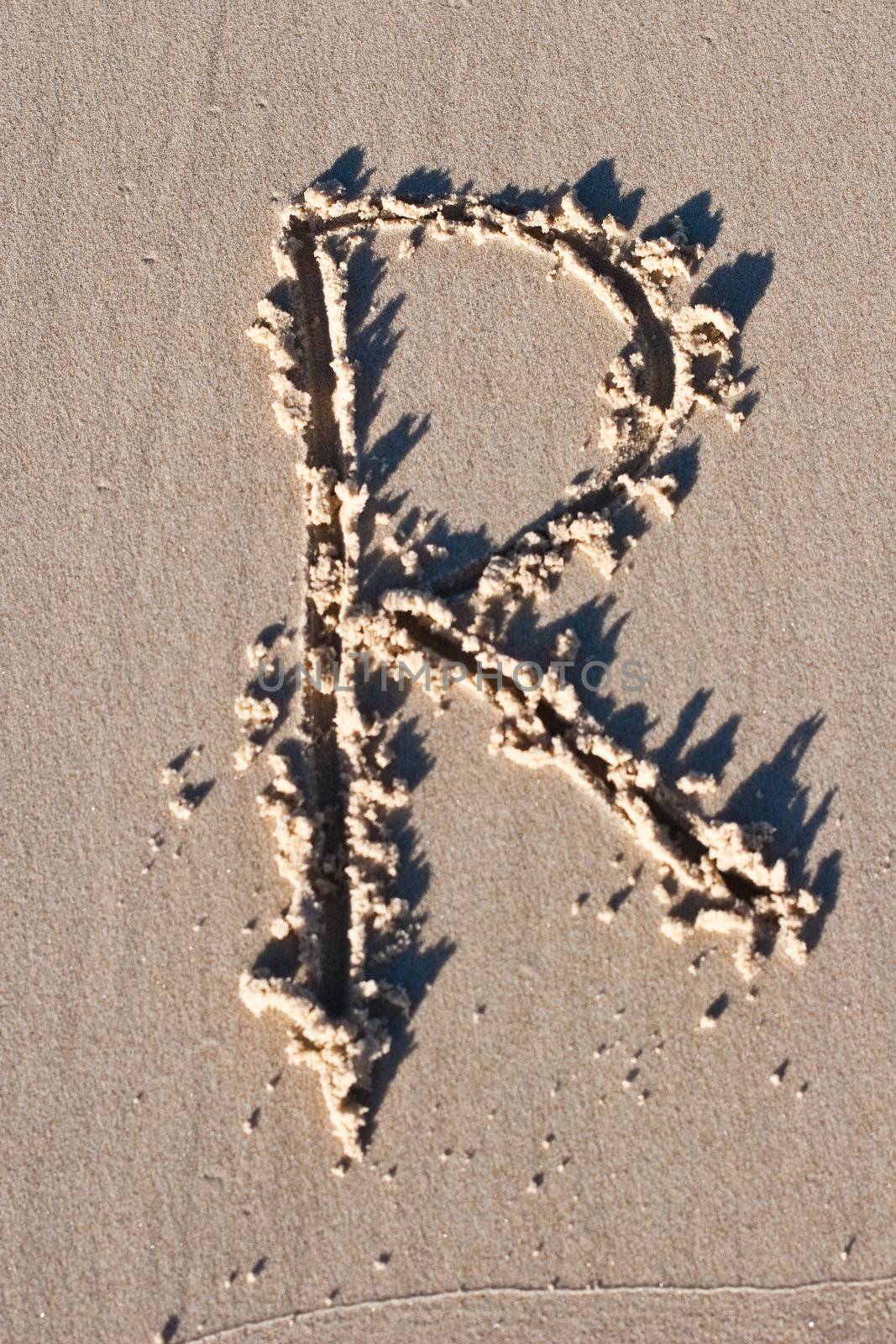 Letter R drawn in the sand. 