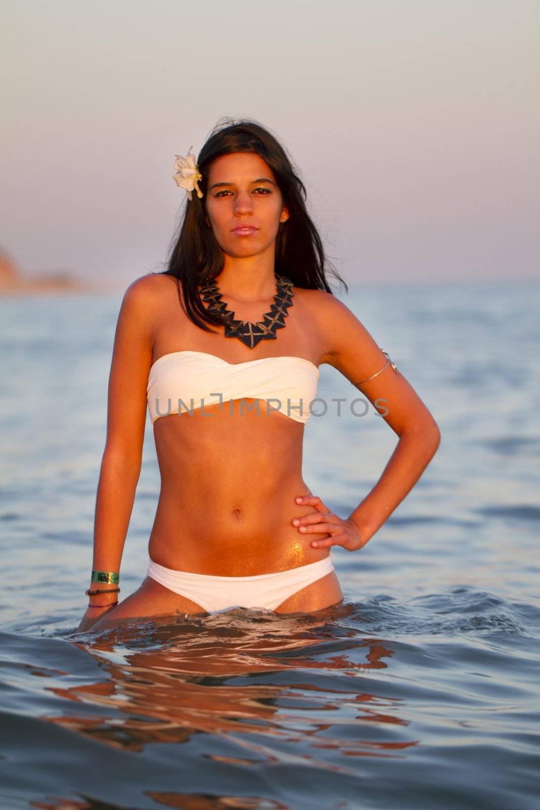 View of a beautiful young girl with a bikini standing on the shore.