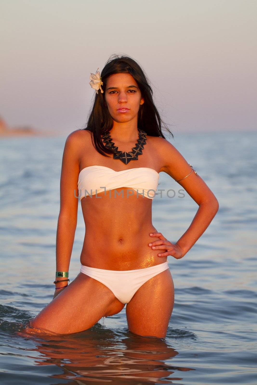 View of a beautiful young girl with a bikini standing on the shore.