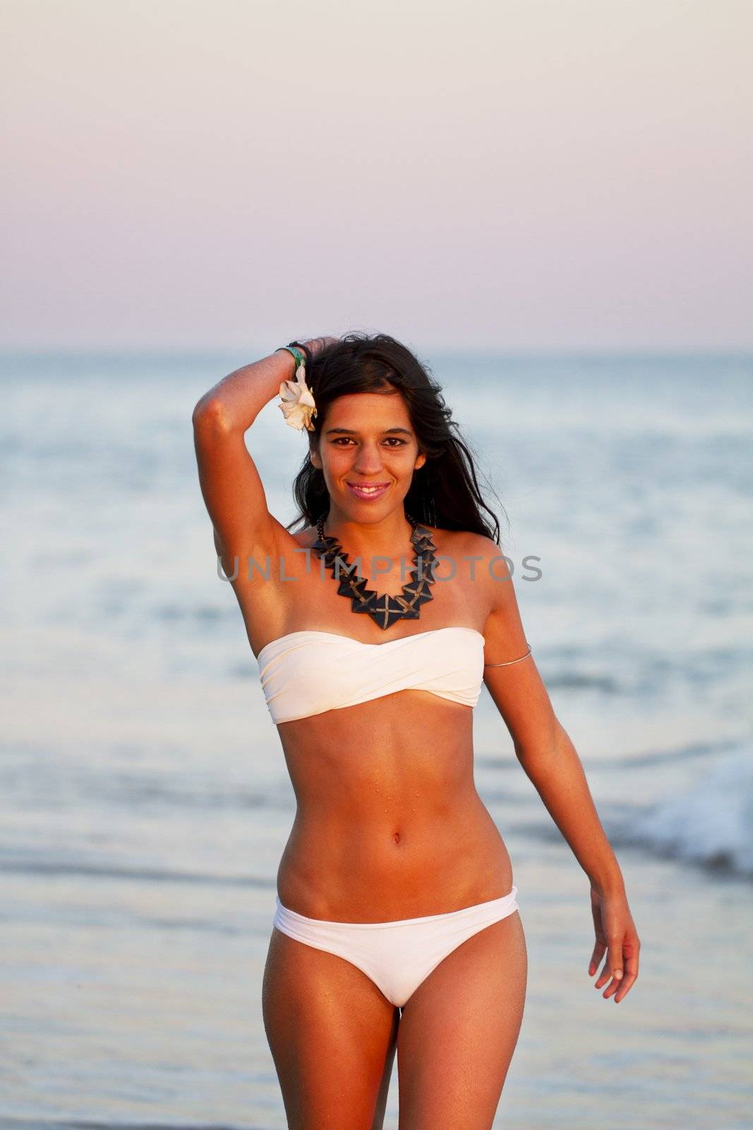 View of a beautiful young girl with a bikini standing on the shore.