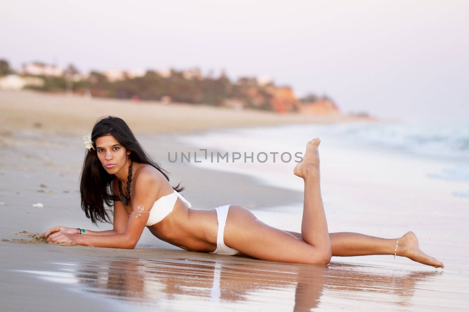 View of a beautiful young girl with a bikini standing on the shore.