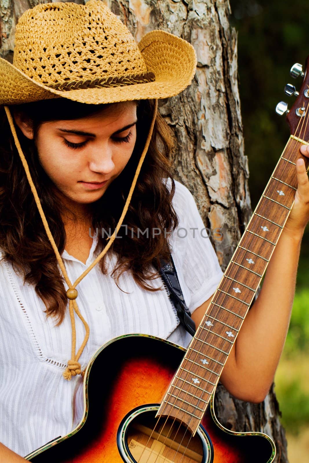 View of a beautiful young country girl with a guitar on the woods. 