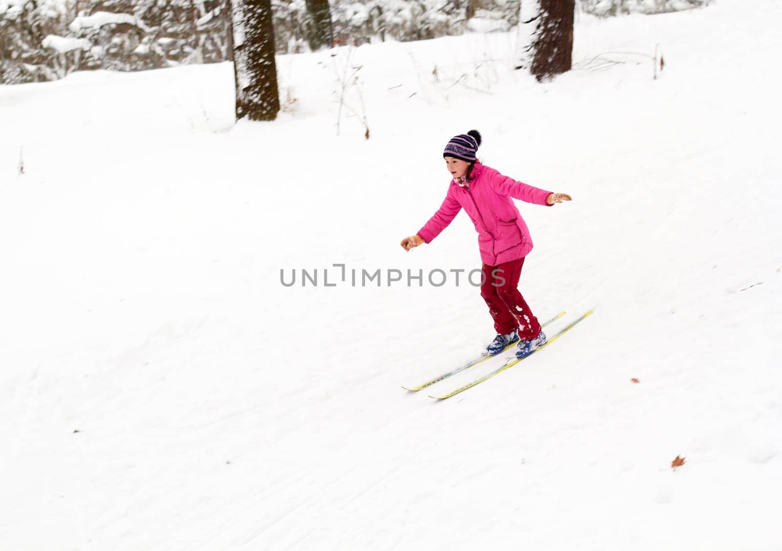 Little girl skiing fast down the hill in snow winter day