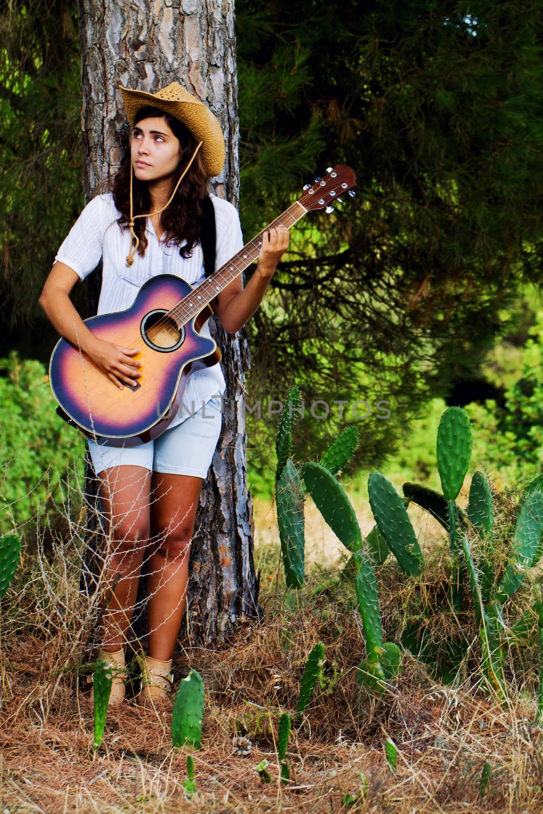 View of a beautiful young country girl with a guitar on the woods. 