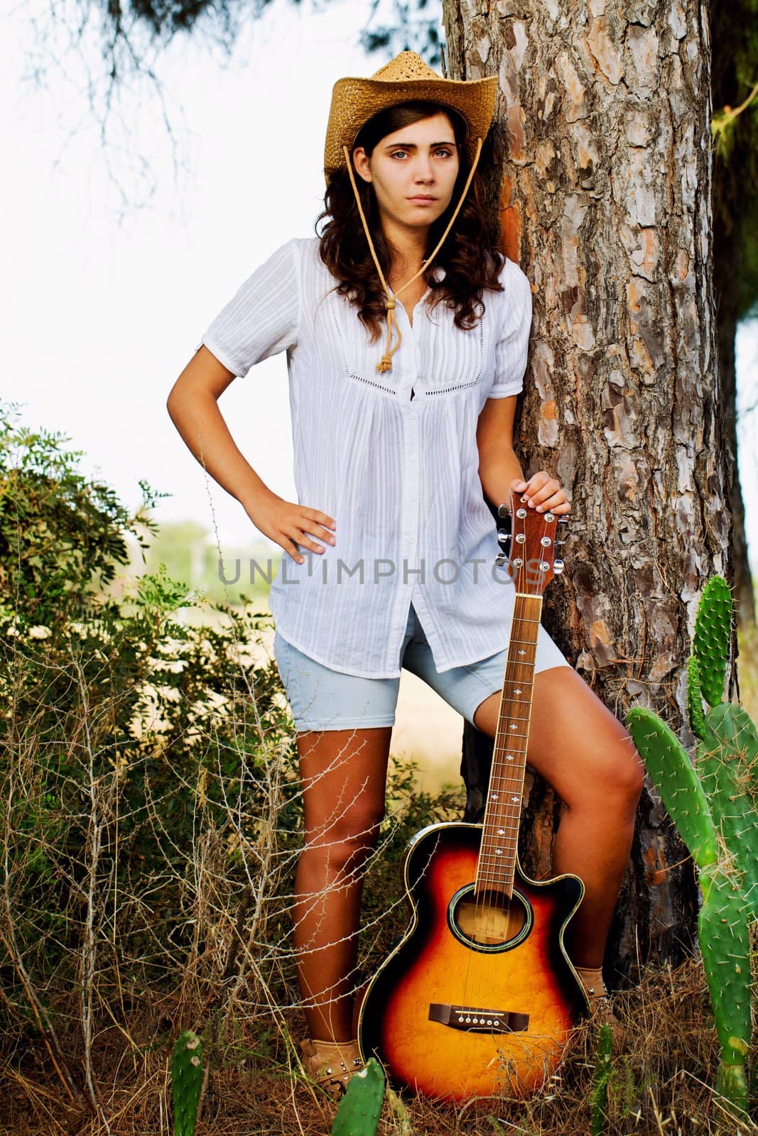 View of a beautiful young country girl with a guitar on the woods. 