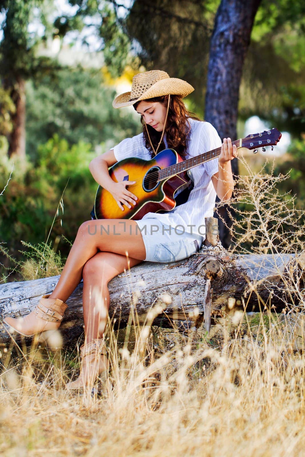 View of a beautiful young country girl with a guitar on the woods. 