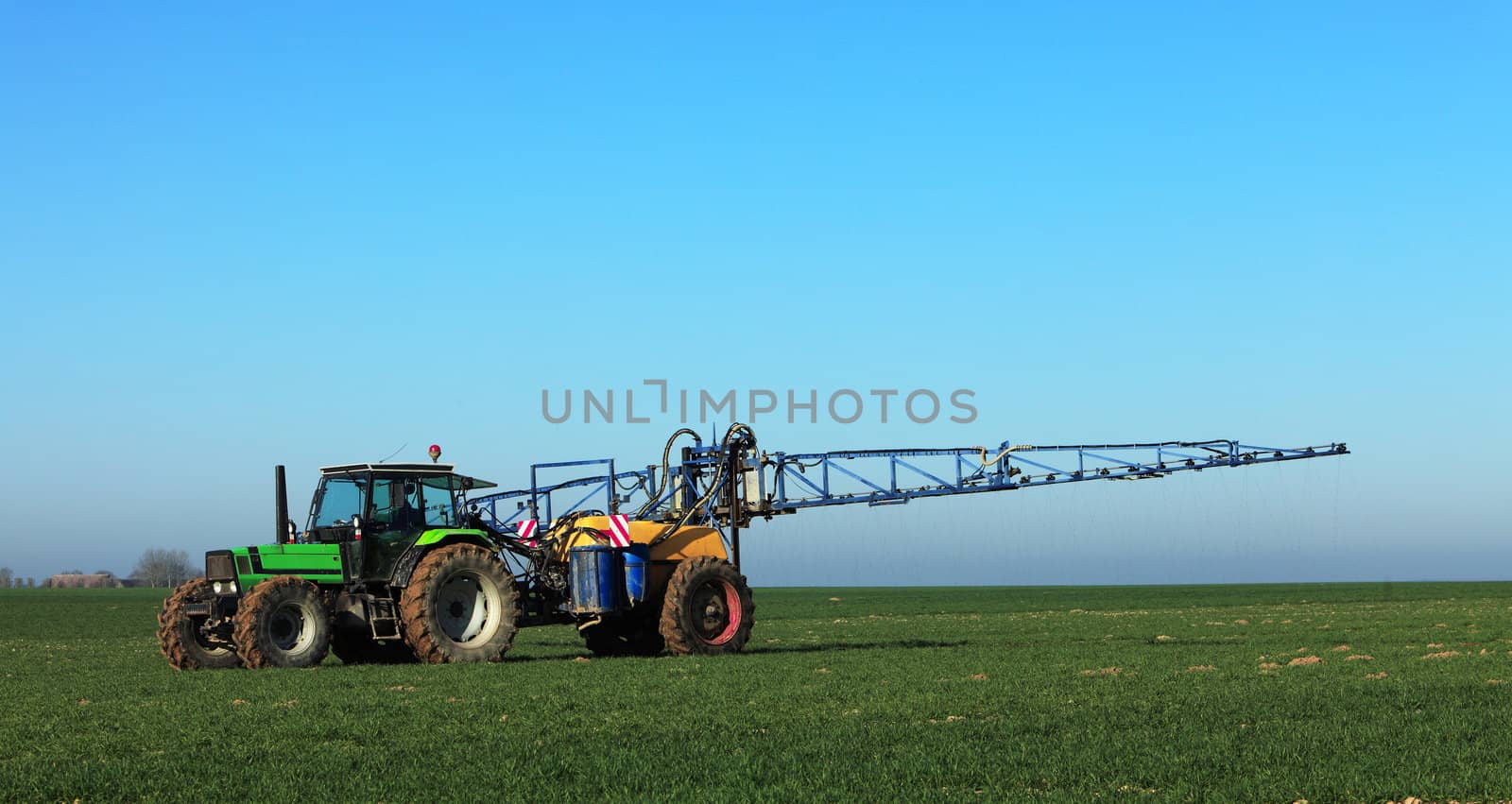 A tractor spreading substances in the early spring in a field in Central region of France.