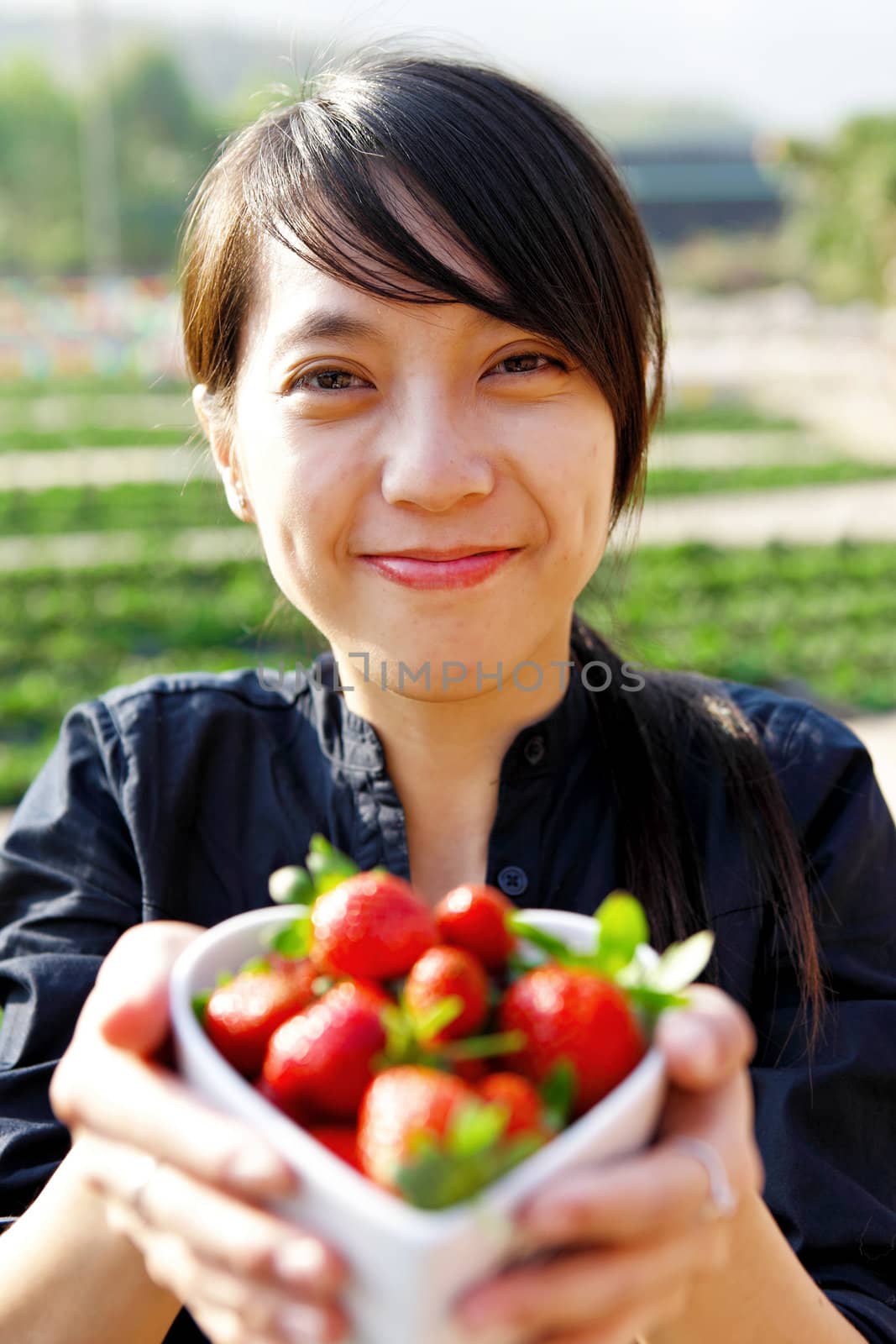 smile girl give you bowl of strawberries by leungchopan